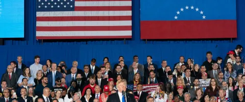 Donald Trump pronunciando un discurso con las banderas de Estados Unidos y Venezuela de fondo